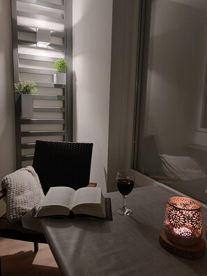 A cozy reading nook with a chair, a table, an open book, a glass of red wine, and a decorative candle. - Haus Atlantic Apartment 213 direkt am Strand in Cuxhaven (Cuxhaven)