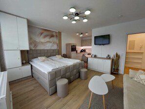 A modern bedroom with a large bed, a TV, a kitchenette, and a seating area. - Haus Atlantic Apartment 213 direkt am Strand in Cuxhaven (Cuxhaven)