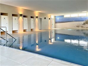 A swimming pool with a clear view of the beach and sky through the adjacent room. - Haus Atlantic 213 Apartment, right on the beach in Cuxhaven (Cuxhaven)