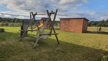 Een speeltuin met een schommel, een glijbaan en een houten speelhuisje.