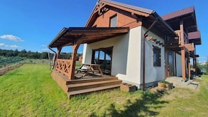 A modern house with a wooden porch and a large window. - Comfortable holiday home with a terrace and garden (Borsk)
