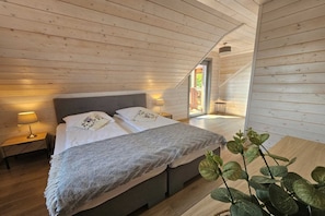 A bedroom with a bed, bedside lamps, and a view of the outdoors.