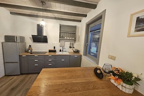 A modern kitchen with grey cabinets, a wooden dining table, and a window with a view.