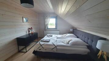 A bedroom with a bed, a dresser, a window, and a lamp.