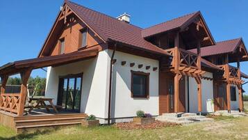 Une maison à deux étages, avec une façade en bois et un toit recouvert de tuiles rouges.