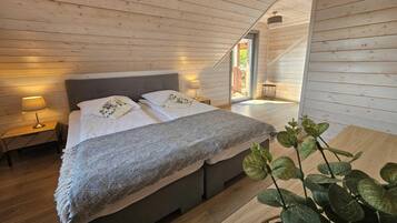 Un dormitorio de cabaña de madera con cama, lámparas de noche y vistas al exterior.