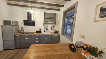 Una cocina moderna con armarios grises, una mesa de comedor de madera y un ventanal con vistas.