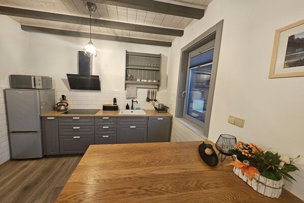 A modern kitchen with grey cabinets, a wooden dining table, and a window with a view.