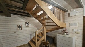 Una escala de fusta en una habitació amb parets de fusta blanca i un armari blanc.