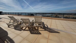 Una terraza con mobiliario exterior y vistas a la costa.