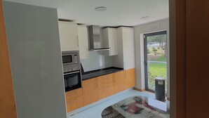 Una cocina moderna con armarios blancos, encimera negra y ventana con vistas a un jardín.