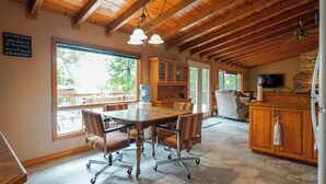 Un comedor espacioso con una mesa y sillas de madera, ventanas amplias y una chimenea de piedra.