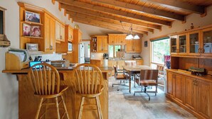 Una cocina amplia con armarios de madera, un comedor con mesa y sillas, y un ventanal que proporciona luz natural.