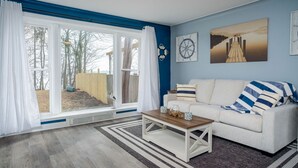 A living room with a sofa, coffee table, and artwork on the wall. - Mineola Extended-Stay Furnished 30-Day+ Cottage (Fox Lake)