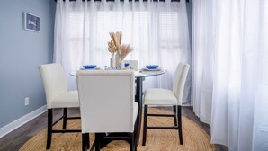 A dining area with a round table, two chairs, and a vase with dried plants. - Mineola Extended-Stay Furnished 30-Day+ Cottage (Fox Lake)