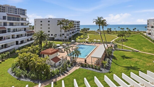 Ein Resort mit Schwimmbad, Palmen und Blick aufs Meer.