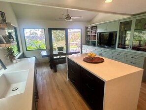 Una cocina moderna con una isla central, armarios oscuros y un amplio ventanal con vistas al exterior.