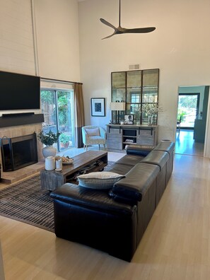 A modern living room with a fireplace, leather sofa, coffee table, and a large mirror. - Casa Sharman in Solana Beach welcomes you to live with ease and joy. (Solana Beach)