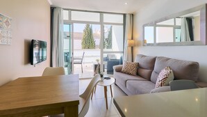 Ein modernes Wohnzimmer mit einer Couch, einem Esstisch und einem an der Wand befestigten Fernseher.
