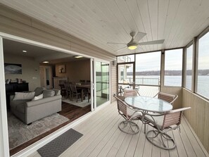 Ein geräumiger Balkon mit Tisch und Stühlen, einem Deckenventilator und Blick auf das Wasser.