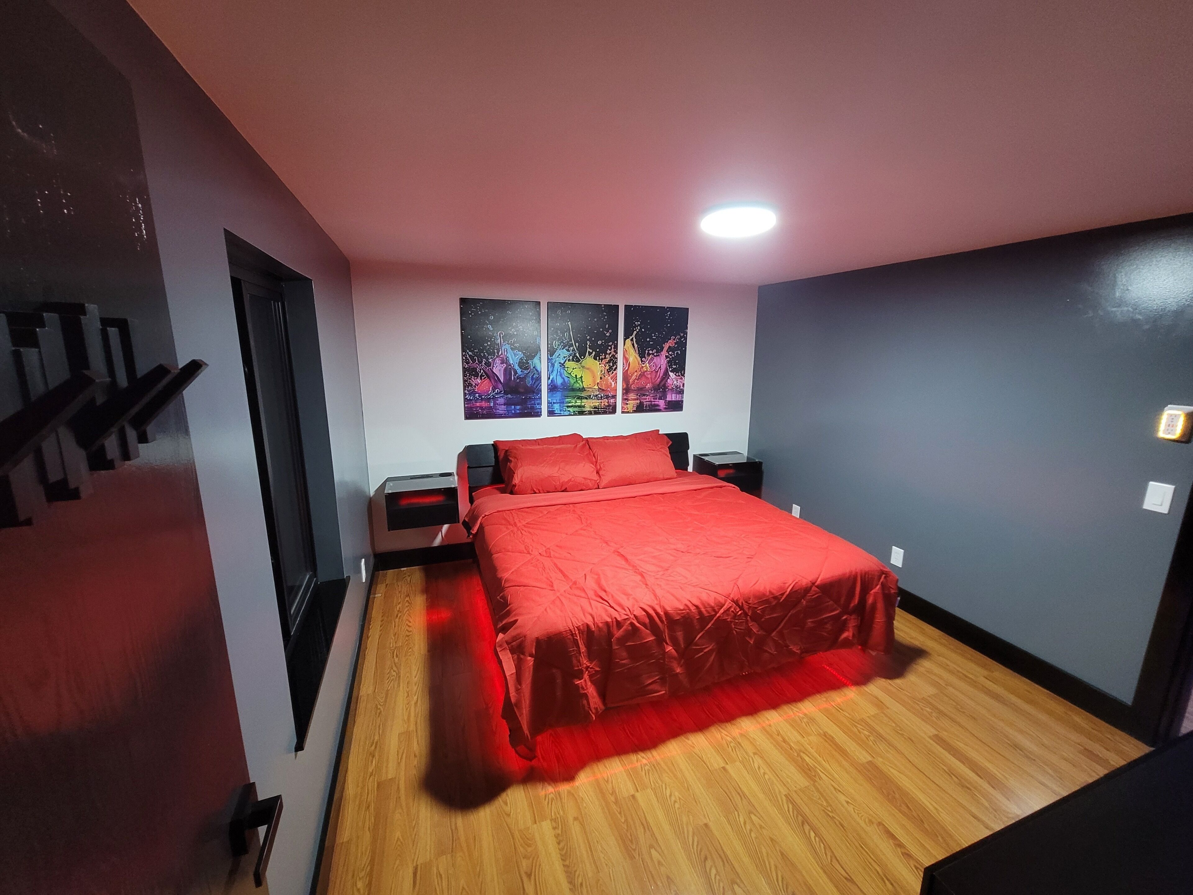 A bedroom with a bed, nightstands, a wall-mounted shelf, and two wall art pieces.
