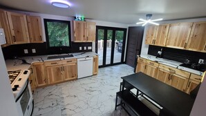 Une cuisine moderne avec des meubles en bois, un four encastré et un coin repas doté d’une banquette.