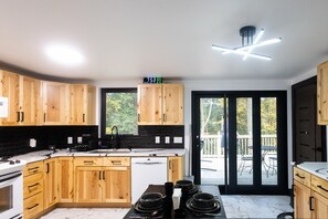 Una cocina moderna con armarios de madera, un reloj digital y vistas al exterior a través de una puerta corredera de vidrio.
