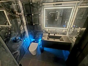 Une salle de bain moderne avec une paroi de douche en verre, des toilettes et un lavabo.