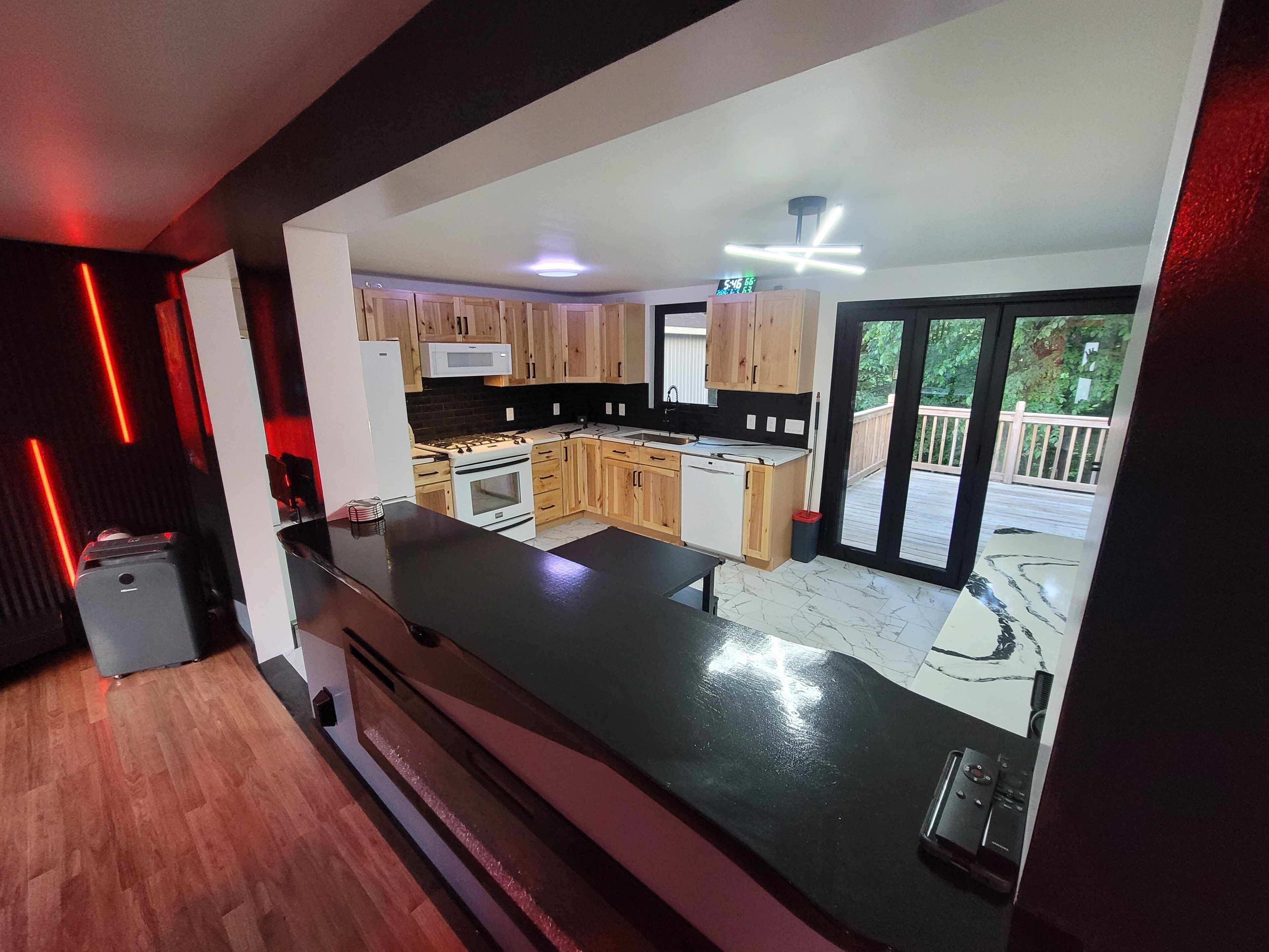 A modern kitchen with wooden cabinets, a black countertop, and a view of a deck.