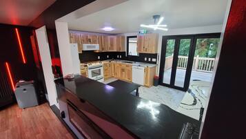 A modern kitchen with wooden cabinets, a black countertop, and a view of a deck.