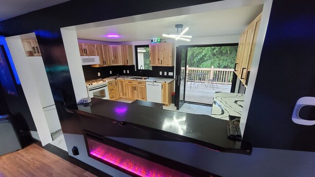 Une cuisine moderne avec des meubles en bois, une cuisinière encastrée et une grande fenêtre donnant sur une terrasse.