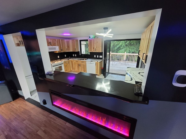 A modern kitchen with wooden cabinets, a built-in stove, and a large window overlooking a deck.