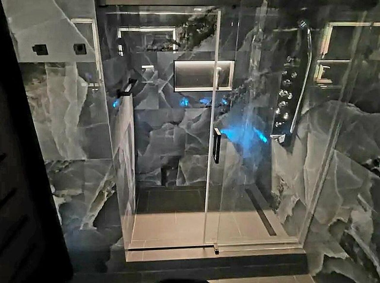 A glass-enclosed elevator with a control panel and a metallic door.