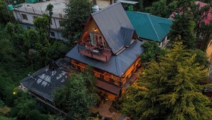 A multi-story house with a prominent attic room, surrounded by dense greenery. - The Divine Hima (Dharamshala)