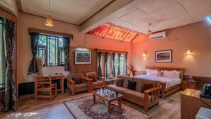 Una habitación acogedora con cama, sofá, sillas, una mesita y una ventana con cortinas.