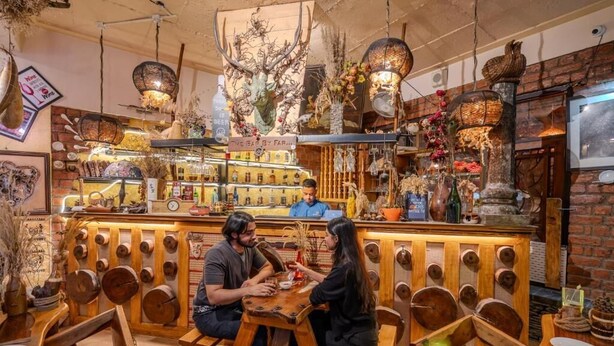 A rustic interior with wooden furniture, a bar area, and various decorative items. - The Divine Hima (Dharamshala)