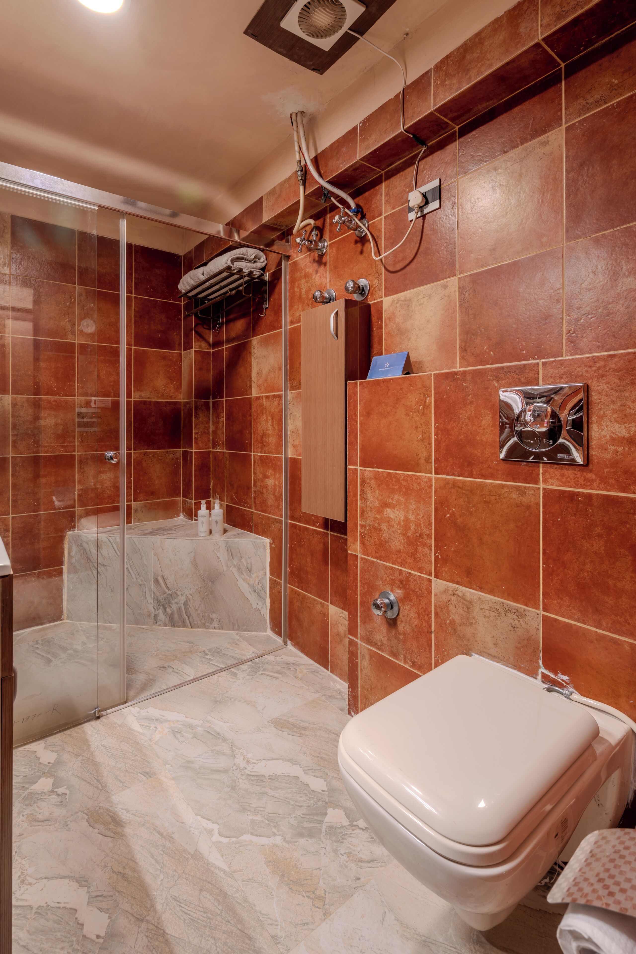 A bathroom with a glass-enclosed shower, a marble sink, and a toilet.