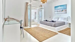 Un dormitorio moderno con cama, escritorio y silla, lámpara colgante y un cuadro en la pared.