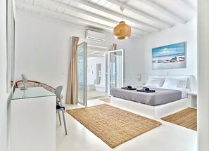 Ein modernes Schlafzimmer mit Bett, Schreibtisch mit Stuhl, einer Pendelleuchte und einem Bild an der Wand.