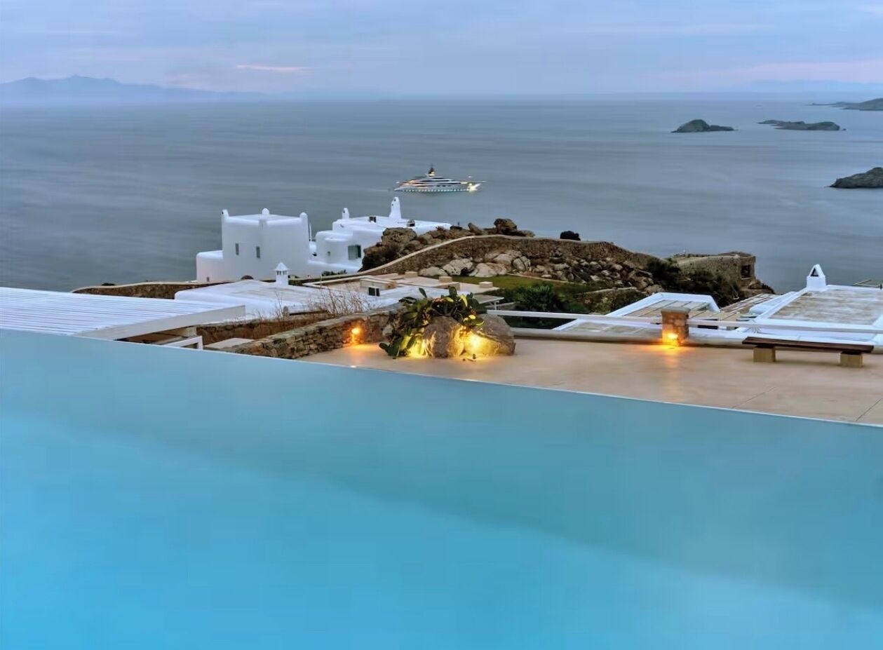 Vista della piscina con vista sul mare e una nave da crociera all'orizzonte.