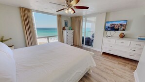 Ein Schlafzimmer mit einem großen Bett, einem Deckenventilator, einem Fernseher und Blick auf den Ozean.