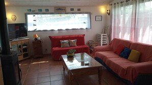 Un salón acogedor con un sofá rojo, una mesa de centro de madera y un televisor sobre un mueble de madera.