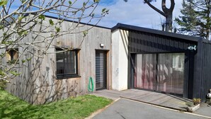 Un edificio moderno con fachada de madera, amplios ventanales correderos y un garaje visible.