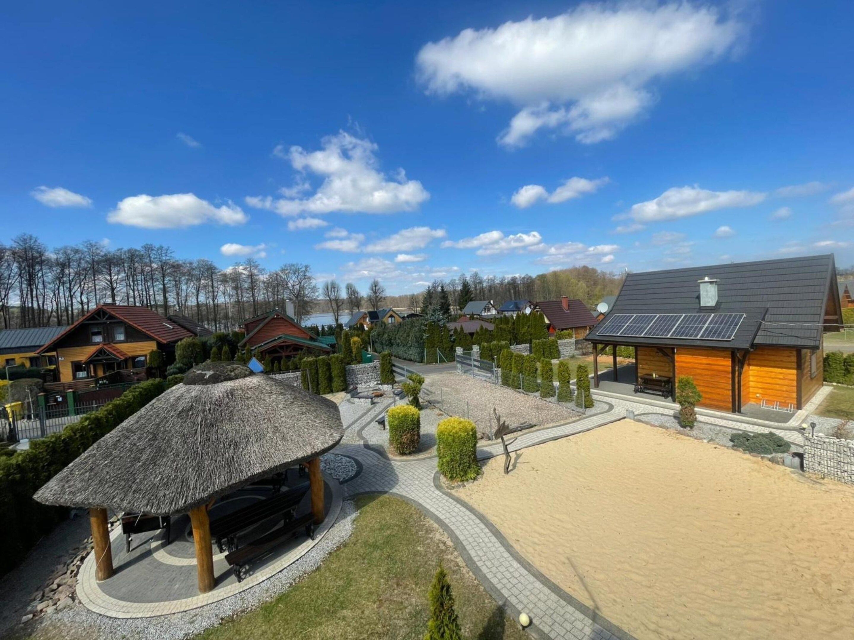 Un complexe hôtelier doté d’une plage de sable, d’une structure à toit de chaume et de bâtiments modernes équipés de panneaux solaires.