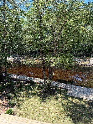 A wooden deck, a small pond, and dense trees. - Peaceful Canal Retreat - 2 bed/2 bath home and only 30 mins to Panama City Beach (Vernon)