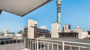 Une terrasse sur le toit offrant une vue dégagée sur les bâtiments modernes, dont une tour remarquable.