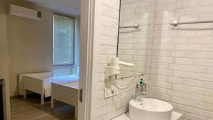 A bathroom with a white sink, a mirror, and a towel rack. There is a bench in the adjacent room. - Boutique Hotel Meidan View (Tbilisi)