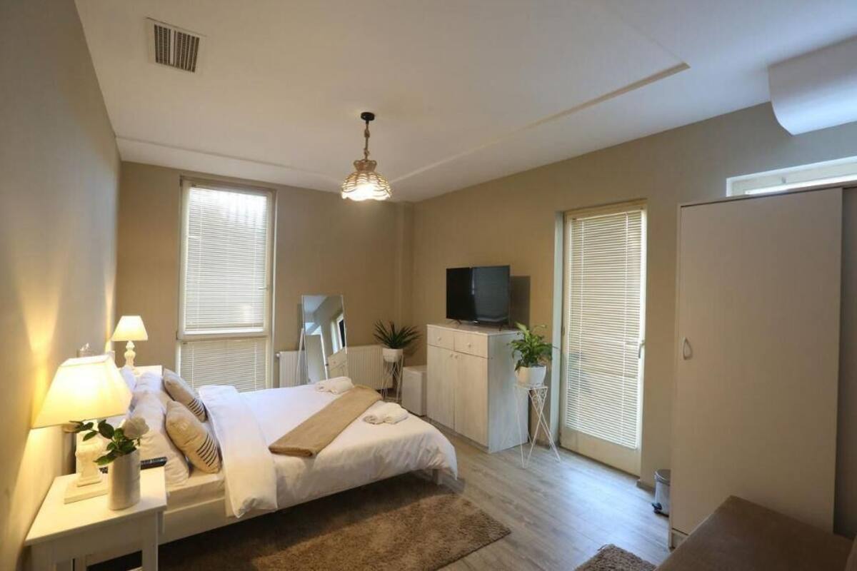 Une chambre à coucher avec un lit, des lampes de chevet, une télévision, une commode et une fenêtre.