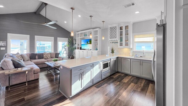 A modern kitchen with a central island, grey cabinetry, and a large window overlooking a scenic view. - Seashell Shack on Shrimp, Sleeps 11 - 3 bedroom 2.5 Bath - Great View (Crystal Beach)