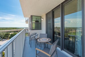 Un balcon avec une table et des chaises, une vue sur une autoroute et un bâtiment en arrière-plan.